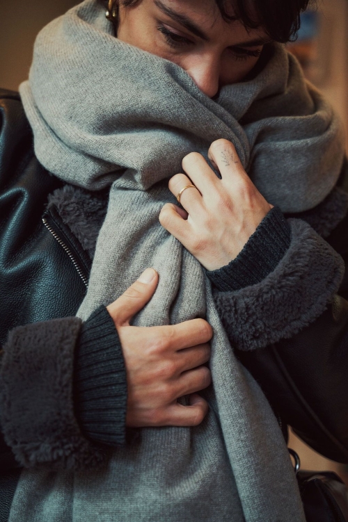 Une femme portant une écharpe grise en cachemire, emmitouflée pour se protéger du froid.